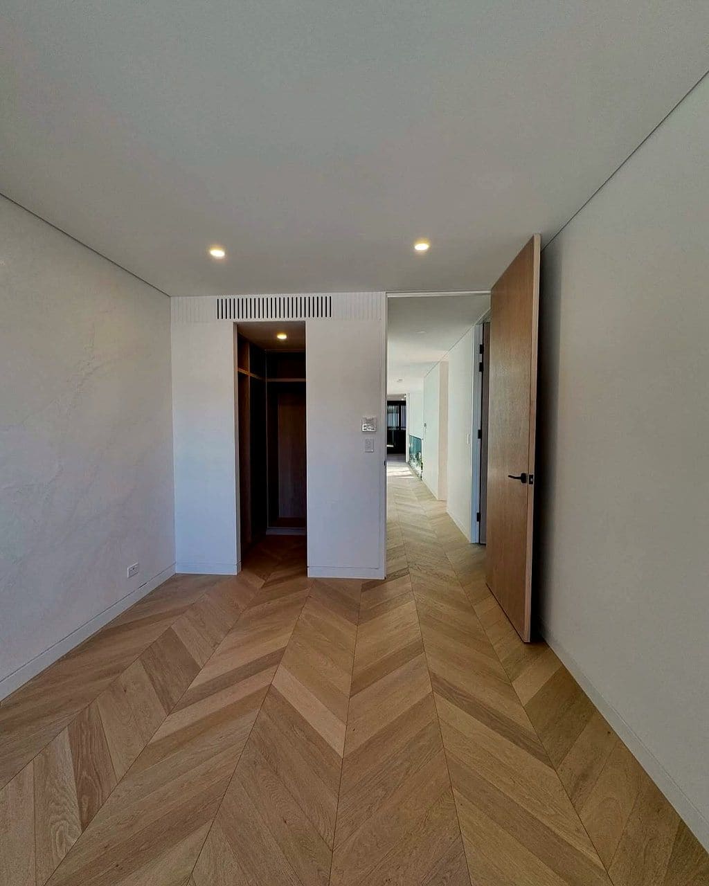 Chevron oak flooring down a hallway, each board mitred to meet its neighbour in a point