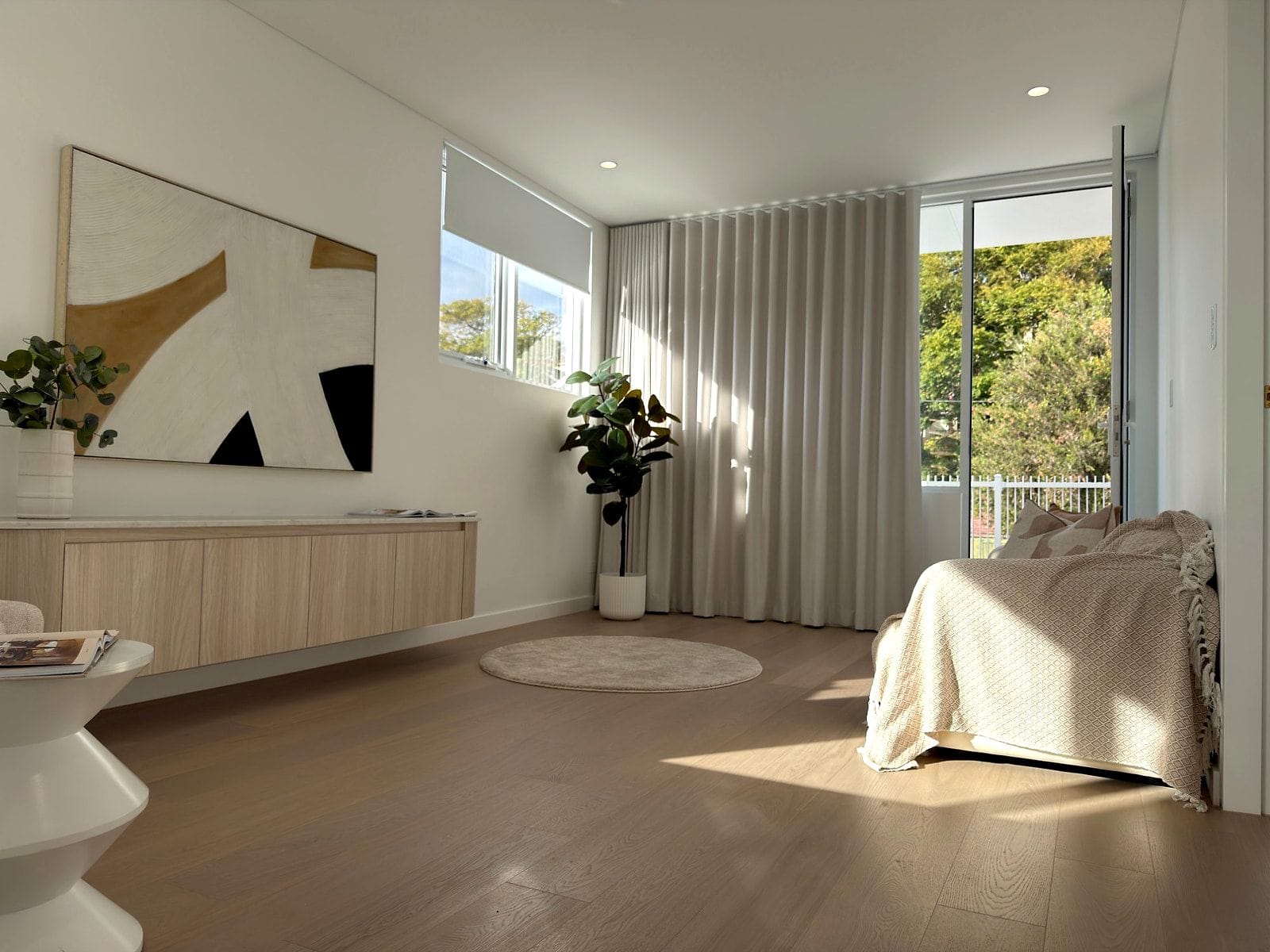 Wide straight-plank flooring in a sunlit sitting room with floor-to-ceiling curtains