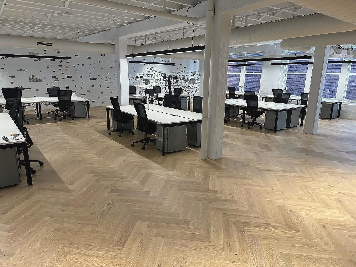 Commercial office fit-out with herringbone flooring running beneath rows of desks