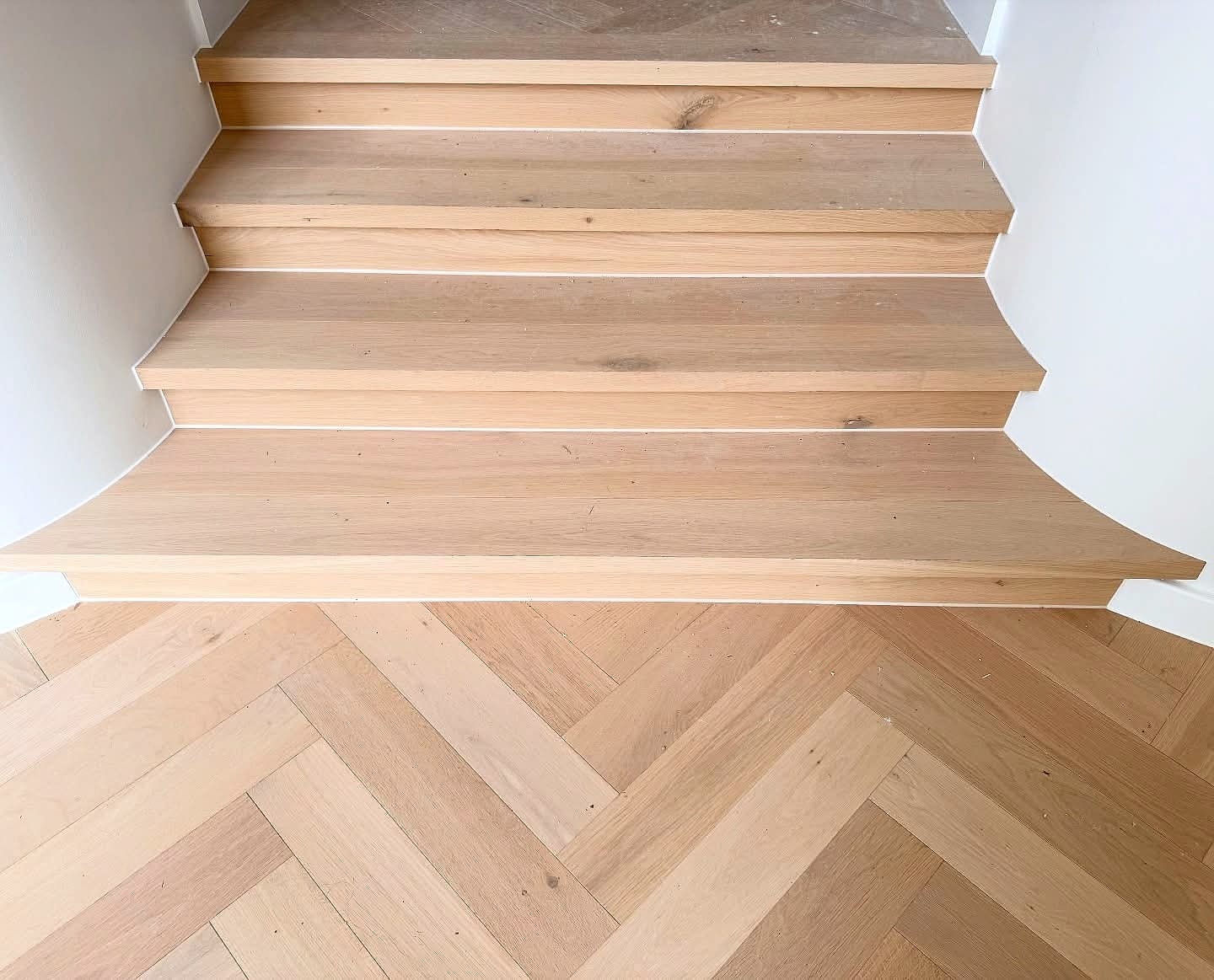 Herringbone flooring meeting the base of a timber staircase